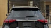 Rear view of a black Mercedes-Benz GLE SUV parked in a driveway; prominent Mercedes emblem, dual exhausts, and a license plate holder on the tailgate. Watermark text across rear window reads 'AUTOMOTIVENG PREMIUM'.