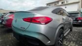 Silver Mercedes SUV parked in a lot, rear three-quarter view on a cloudy day, showing the taillights, quad exhausts, and sporty rear bumper.